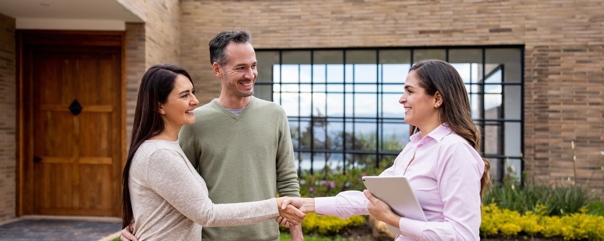 Agent immobilier saluant un couple avec une poignée de main