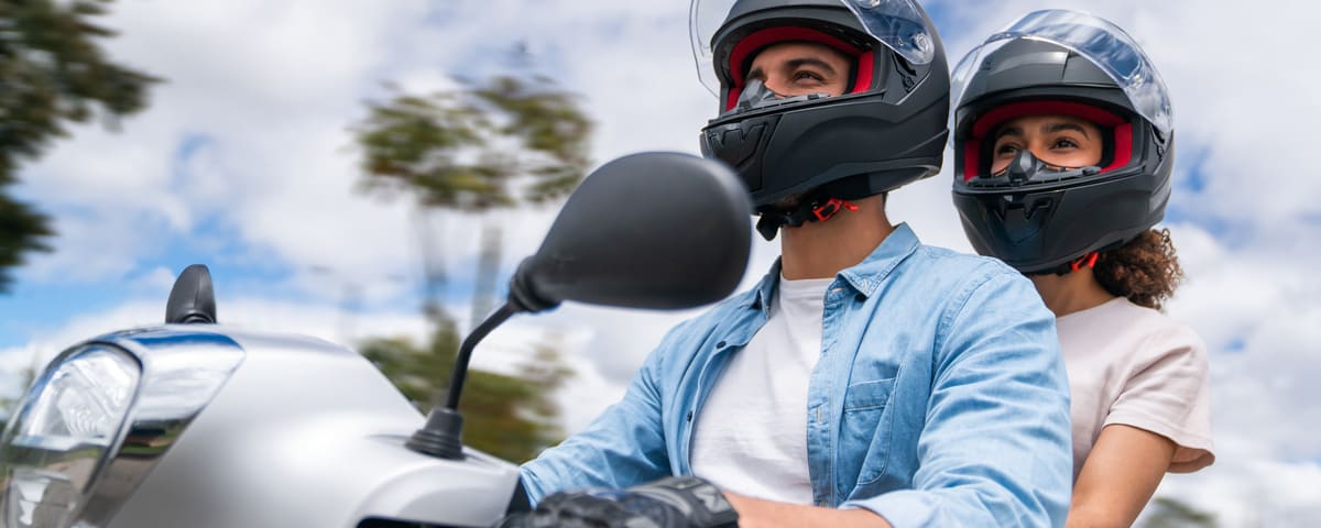 Couple portant un casque roulant sur une moto, illustrant l'achat d'une moto financé par un prêt personnel