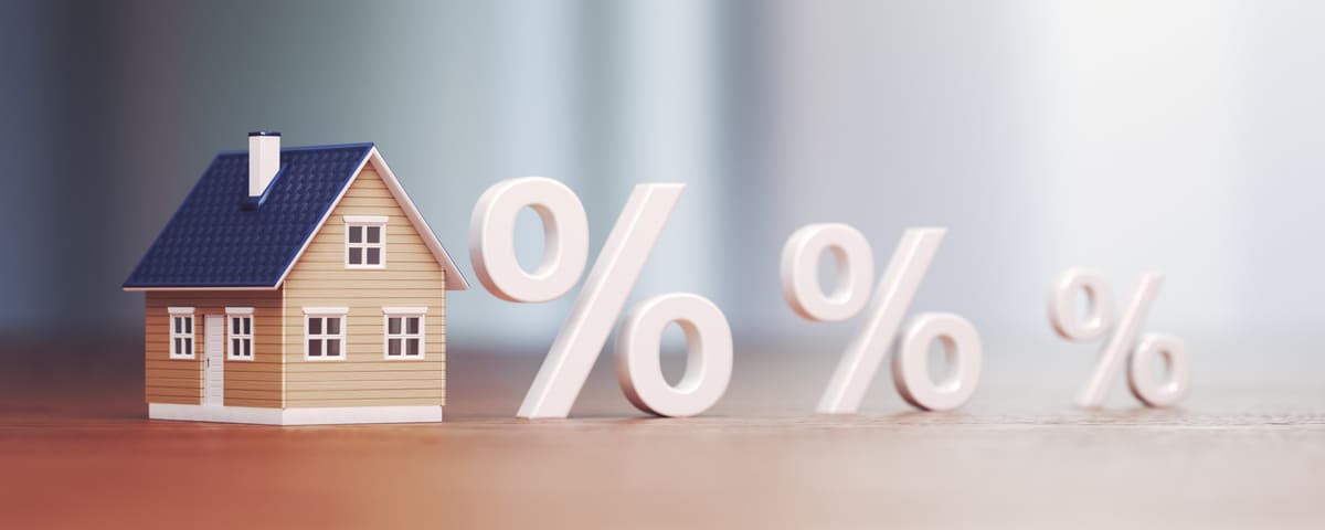 Une maison miniature accompagnée de symboles de pourcentage illustre la hausse attendue des taux de crédit immobilier en 2025.