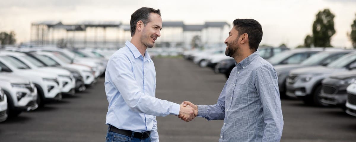  hommes qui se serrent la main apres l'achat d'un vehicule d'occasion 